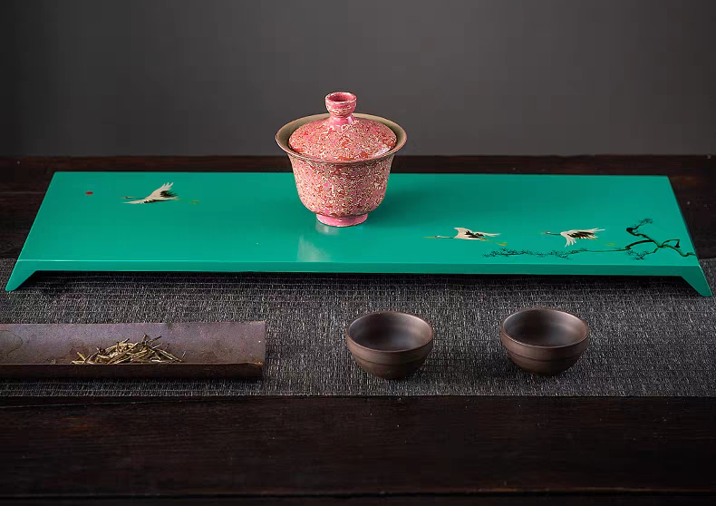 A traditional Japanese lacquerware tea set featuring a teapot and cups on a wooden tray, showcasing exquisite Maki-e gold inlay design.