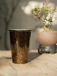 Handmade lacquer tea cup beside incense in a quiet tea setting