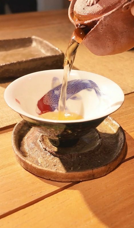 Warm Chinese tea being poured from a handmade teapot