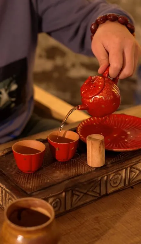Person using a handmade tea vessel during a quiet everyday ritual at home