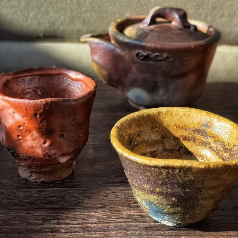 A few handmade vessels displayed with generous space on a shelf in a quiet contemporary home.