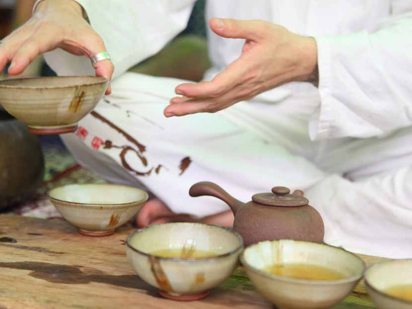 Hand holding a handmade tea cup shaped by years of daily use