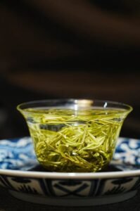 loose tea leaves opening in hot water during a traditional tea brewing process