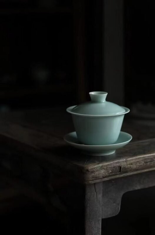 Handmade tea bowl on wooden table beside warm tea