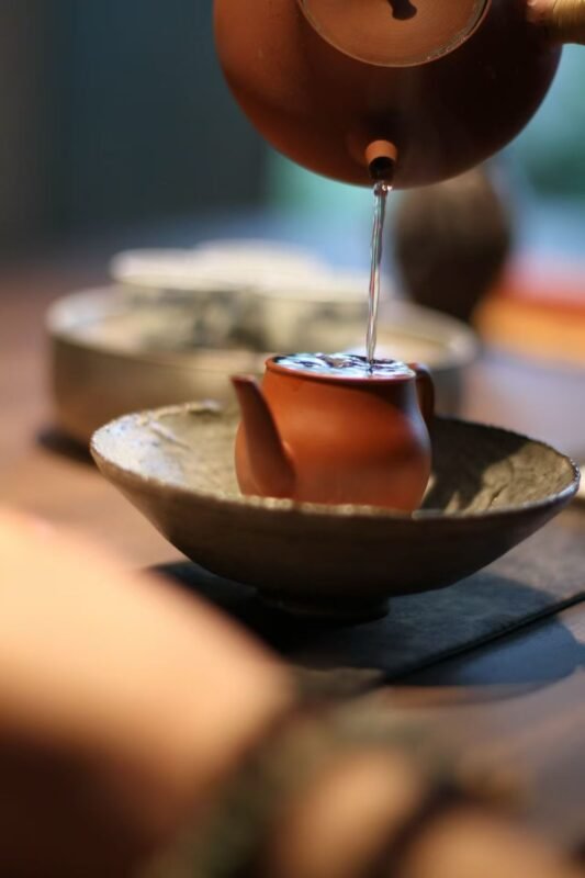 Warm tea being prepared slowly in a quiet tea setting
