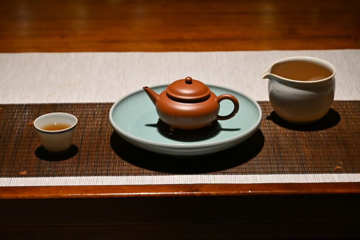 Hand touching the smooth surface of lacquer, textured ceramic, and glazed celadon vessels