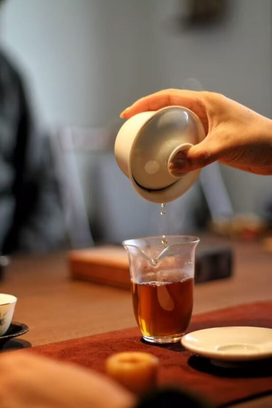 Hand holding a quiet handmade tea gaiwan during a tea ritual