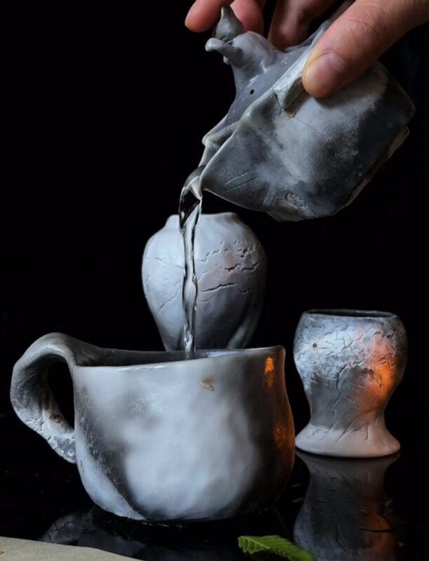 Hand holding a handmade clay tea bowl with rising steam