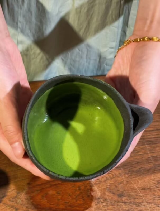 Top view of handmade clay tea bowl filled with tea
