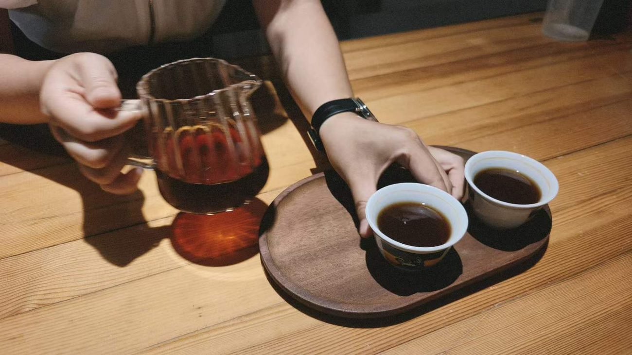 Two people sharing tea from handmade cups during a relaxed conversation at home