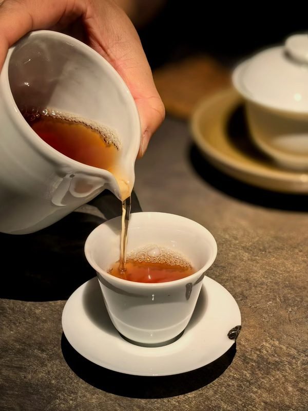 Tea being poured into a handmade ceramic cup as part of a slow tea preparation ritual